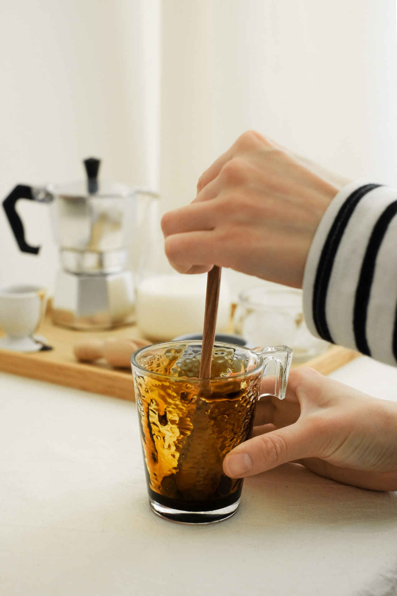 Woman Mixing Coffee in Glass Mug with Syrup